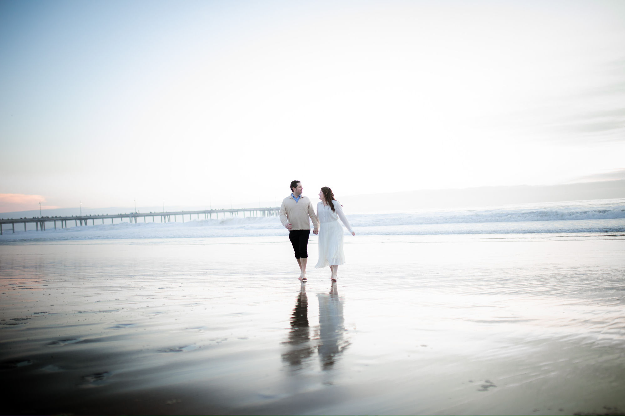 Couple walking hand in hand on Venice Beach at sunset